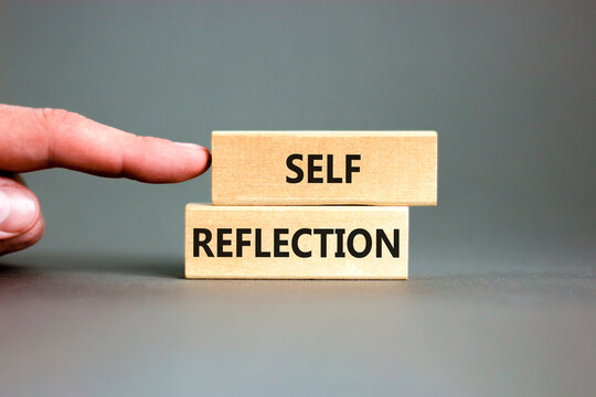 Self reflection symbol. Concept word Self reflection typed on wooden blocks. Beautiful grey table grey background. Businessman hand. Business psychological and self reflection concept. Copy space.