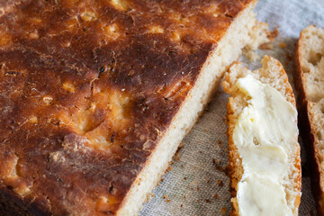 Homemade artisan bread and slices of buttered bread, close-up. Concept of breakfast or healthy food