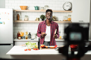 African man filming cooking vlog. Happy man filming his blog about healthy food at home