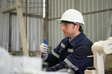 Young male engineers with experience are maintaining and testing the functionality of welding robots