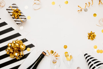 Christmas party composition. Gifts, hats, champagne bottle black and gold decorations on white background.