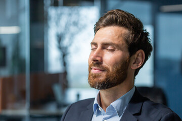 Close-up photo. Portrait of a handsome young man who closed his eyes and rests at the workplace....