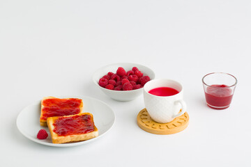 Cup of red tea and toasted bread with raspberry jam