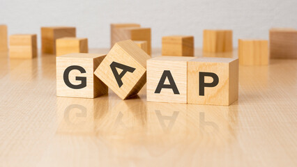 four wooden blocks with text GAAP on table. copy space. white background.