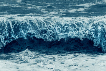 Dark blue dramatic sea storm. Ocean water bubbling near coast shore with lot of foam.
