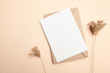 Holiday greeting card mockup with dry grass on beige background, top view, flat lay. White wedding invitation card