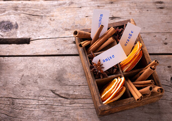 Vintage box with  different spices - cinnamone, slices of dried orange, anise on aged wooden  background. Top view. Place for text.