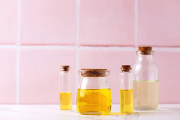 Bottles  with organic essential aroma oil against pink tiled wall. Natural skin care products. Beauty blogging, salon treatment concept. Selective focus. Place for text.