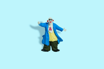 Miniature people toy figure photography. Full body of a bald clown with welcome pose. Isolate on blue background