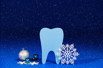 Christmas dentistry - tooth, snowflakes and balls on a blue festive background with snow