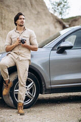Naklejka premium Handsome man travelling by his car and making photos on his camera