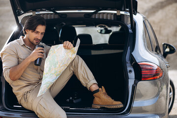Man travelling by his car and reading his map