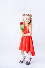 a little happy child girl in a red dress and in her mother's big shoes with a rose in her hand on a white isolated background laughs and smiles, the concept of Valentine's day, a place for text