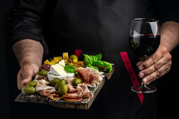male hands hold jamon and a glass of wine on a dark background, Restaurant menu, dieting, cookbook...