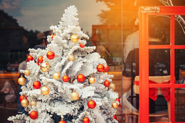 Christmas ball hanging on artificial white pine tree in public park. Stylish christmas decorations. Christmas and New Year display for celebration, carnival, festival design concept. Selective focus.