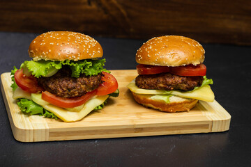 Homemade burgers with cheese and lettuce on wooden board