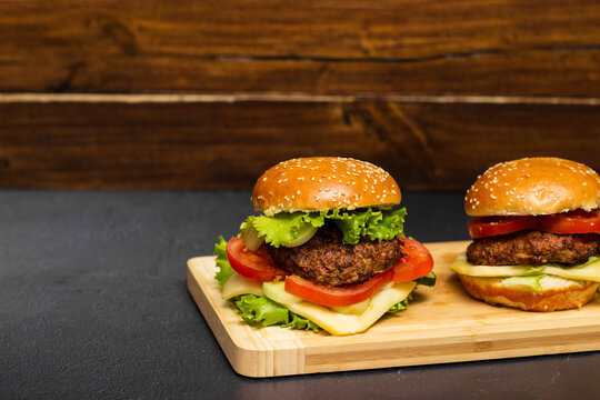 Homemade burgers with cheese and lettuce on wooden board