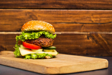 Burger with cheese and lettuce on wooden board