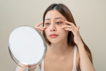 lack of sleep problem, Worried Asian young woman pointing finger at dark circles under her eyes
