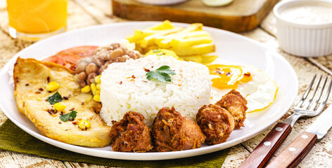 plate of rice and beans typical of Brazil, fried sausage, fried egg, chopped vegetables and salad, brazilian restaurant food