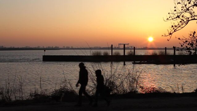 full HD time lapse of strollers in the afternoon at Elbe River in winter at sunset, real time