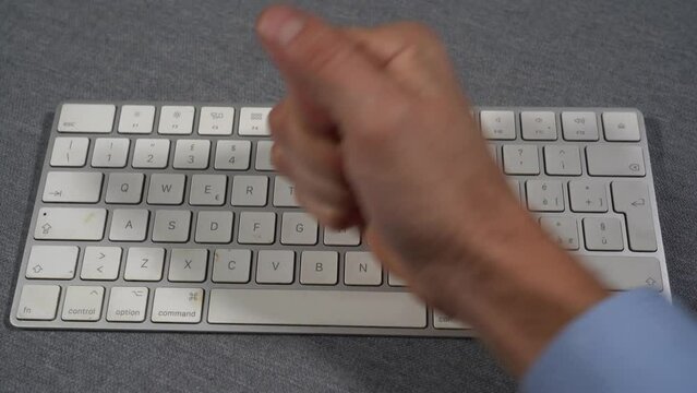 Businessman punches computer and keyboard that doesn't work - problems at work in office and smart working - hysterics against internet and modern technology, online addiction- virus and hackers 