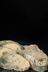Mold on bread on a black background close-up. The danger of mold, stale products.
