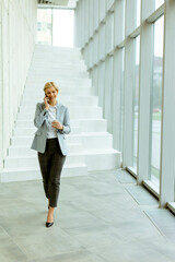 Obraz premium Businesswoman using mobile phone on modern office hallway