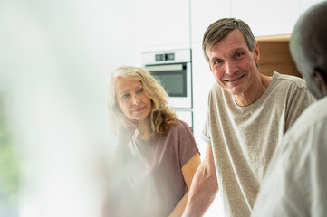 Obraz premium Portrait of middle-aged couple chatting with friends in kitchen
