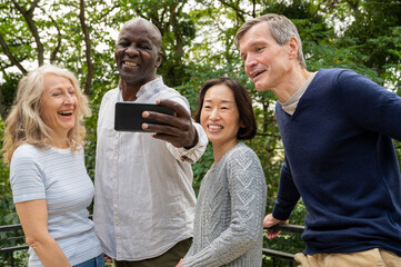 Portrait of diverse couples having fun while taking a selfie in public park