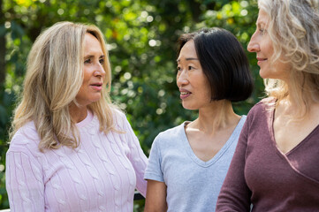 Three middle aged women having a friendly conversation in their backyard