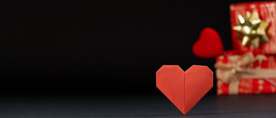 Banner for Valentine's Day, red paper heart and gifts on a black background, origami, place for text.