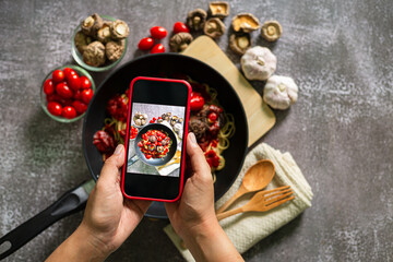 Take a photo of spaghetti with a mobile phone,Top view of woman taking photo on dishes 