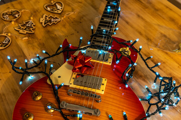 Electric guitar with Christmas lights and ribbon surrounded by Christmas decorations