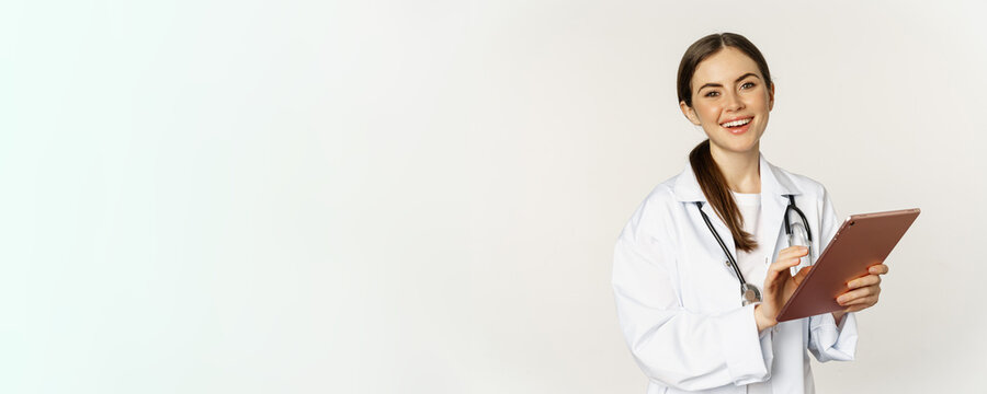 Doctor In White Coat Using Digital Tablet, Reading Medical Data On Gadget, Working In Hospital, Standing Over White Background