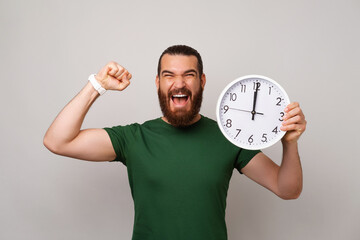 Powerful young man is happy he got all he want in time while holding a clock and making the winner...