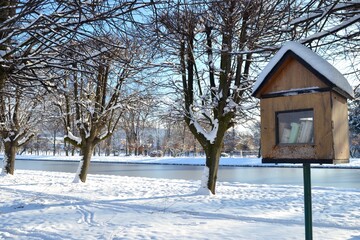 Wooden nesting box turned into free public library. Book box in snowy landscafe of castle park. Winter in Holesov castle. 