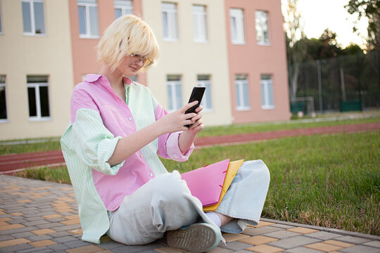 Teenage girl sitting outside and texting via the smartphone.