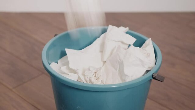 Close-up of crumpled paper wads falling into a bucket. Housecleaning concept