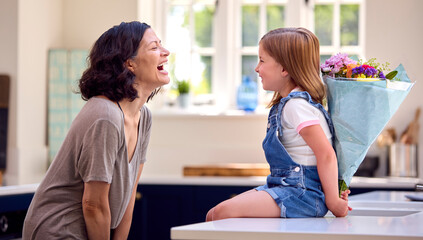 Family At Home With Daughter Giving Older Mother Bunch Of Flowers