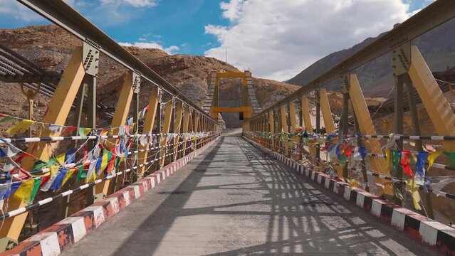  Zoom in shot of Chicham bridge with Buddhist prayer flags fluttering in wind at Spiti Valley, India. Connects the two villages Chicham and Kibber. Highest suspension bridge of Asia. 