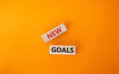New goals symbol. Wooden blocks with words New goals. Beautiful orange background. Business and New goals concept. Copy space.