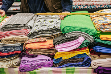 Colorful fabric rolls on counter of textile shop. Hands of salesman working at textile shop
