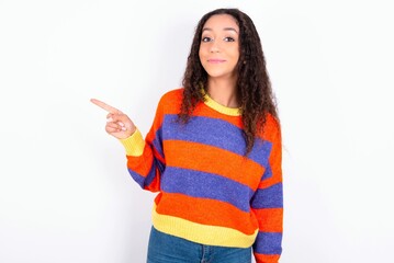 Positive beautiful teen girl wearing striped knitted sweater over white background with satisfied...