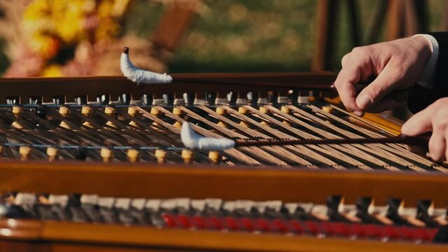 Close up footage of musician playing at cimbalom musical instrument outdoor.