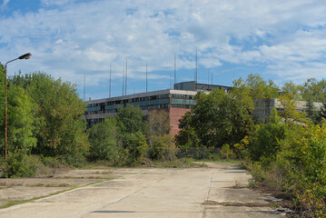 Fototapeta na wymiar Abandoned industrial building overgrown with trees