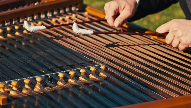 Close up footage of musician playing at cimbalom musical instrument outdoor.