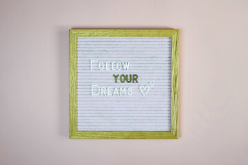 Expression - Follow your dreams - written from white and golden letters on letter board on pink background. Top view. Copy space. Selective focus.