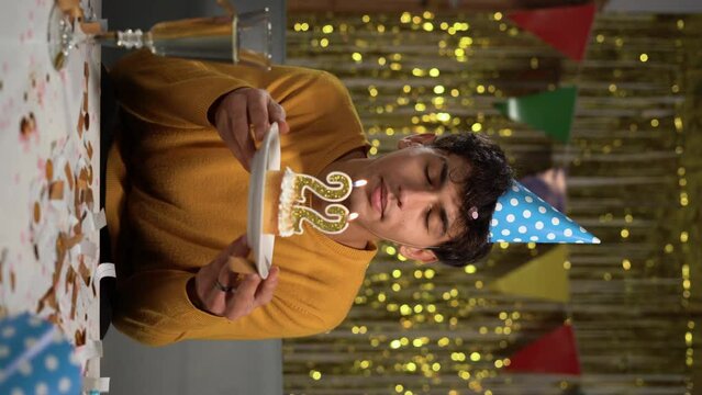 Birthday candles celebrating 22th birthday in cake. Young man making a wish and blowing out the candles celebrate his birthday at home.