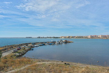 Beautiful sea view on a clear sunny day. You can see the pier with fishing boats and the city on the horizon